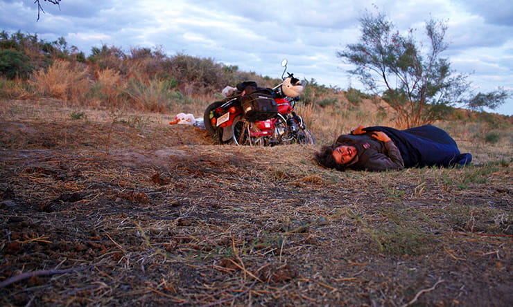 Nathan Millward sleeps on the ground next to his bike